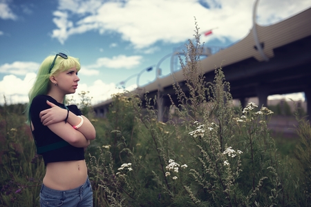Beautiful young swag woman with green hair posing near highway roadの写真素材