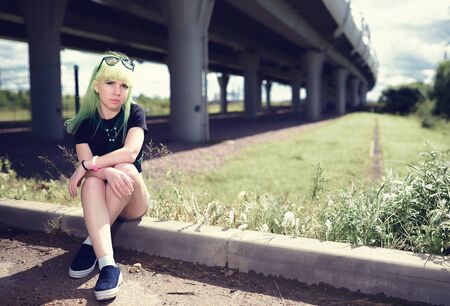 Beautiful young swag woman with green hair posing near highway roadの写真素材
