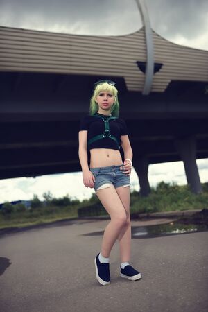Beautiful young swag woman with green hair posing near highway roadの写真素材