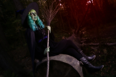 Young girl with green hair and broom in suit of witch in forest. Halloween timeの写真素材