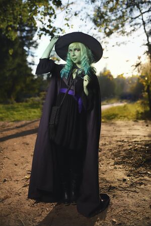 Young girl with green hair and skin suit of witch in forest. Halloween timeの写真素材