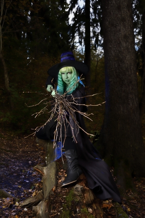 Young girl with green hair and broom in suit of witch in forest. Halloween timeの写真素材