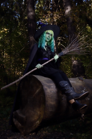 Young girl with green hair and broom in suit of witch in forest. Halloween timeの写真素材