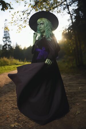 Young girl with green hair and skin suit of witch in forest. Halloween timeの写真素材