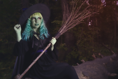Young girl with green hair and broom in suit of witch in forest. Halloween timeの写真素材