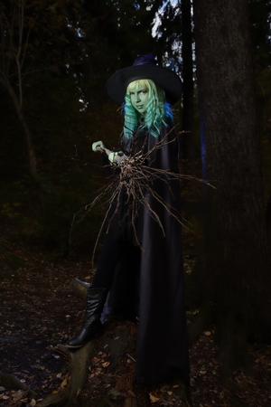 Young girl with green hair and broom in suit of witch in forest. Halloween timeの写真素材