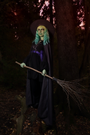 Young girl with green hair and broom in suit of witch in forest. Halloween timeの写真素材
