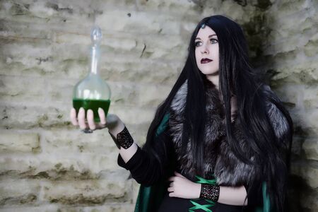 Young girl with fur cape and flask with potion. Looking like Halloween suit.の写真素材