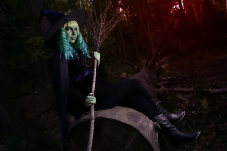 Young girl with green hair and broom in suit of witch in forest. Halloween timeの写真素材