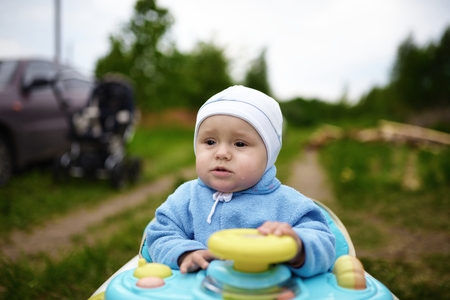 Crying cute baby in baby walker walks outdoorsの写真素材