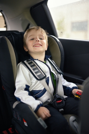 Cute little child sitting in safety car seatの写真素材