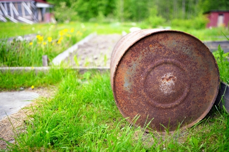 Old rusty barrel against a green grassの写真素材