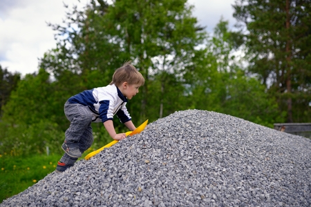 Little boy plays on heap of crushed stoneの写真素材