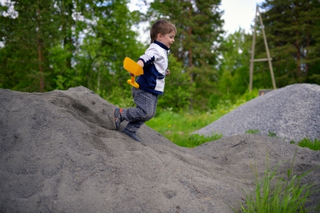 Little boy plays on heap of crushed stoneの写真素材