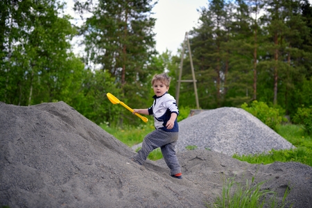Little boy plays on heap of crushed stoneの写真素材