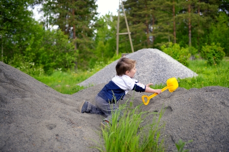 Little boy plays on heap of crushed stoneの写真素材