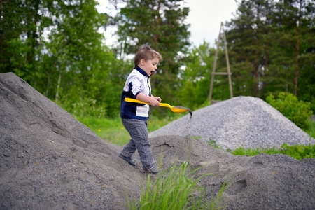Little boy plays on heap of crushed stoneの写真素材