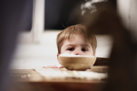 Curious cute child looking over the table edge