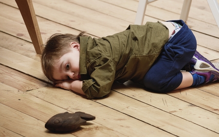 Sorrowful little boy on floorの写真素材
