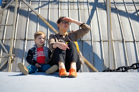 Mother and son sitting on jetty and enjoying beautiful views