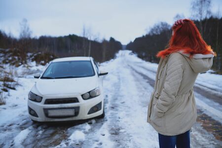 Young redhead girl looks at her broken carの写真素材