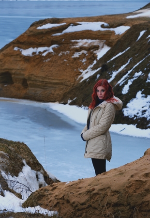 Beautiful redhead girl stays against Nordic landscapeの写真素材