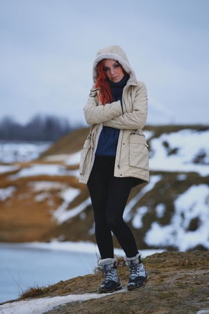 Beautiful redhead girl stays against Nordic landscapeの写真素材