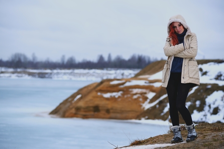 Beautiful redhead girl stays against Nordic landscapeの写真素材