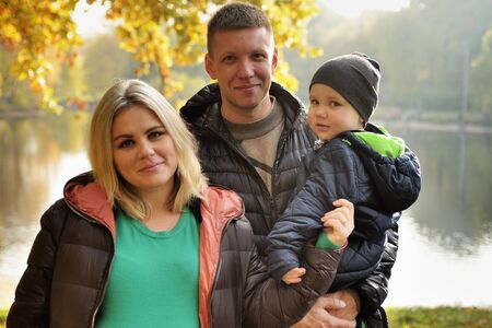 Happy family in autumn park near lakeの写真素材