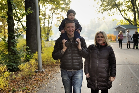 Pregnant young woman walking in autumn park with her husband and childの写真素材