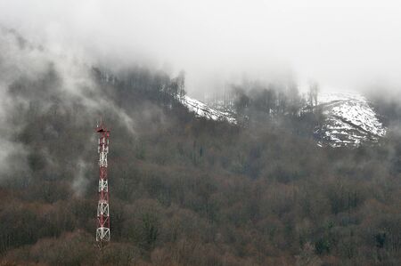 Misty forest on mountain slope in nature reserve with weather stationの写真素材