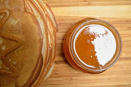 Pancakes and jar of honey on wooden boardの写真素材