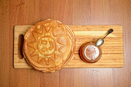 Pancakes and jar of honey with a spoon on a wooden boardの写真素材