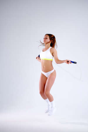 Young active woman with jump rope in studioの写真素材