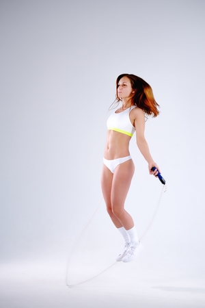 Young active woman with jump rope in studioの写真素材