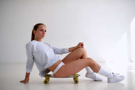 Sexy female model with yellow skateboard on white backgroundの写真素材