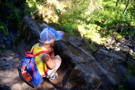 Little boy traveler with backpack sits near gorgeの写真素材