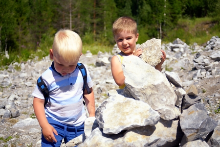 Two little cute boys together building tower of stonesの写真素材