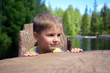 Portrait of a cute boy sits chair near edge of a riverの写真素材
