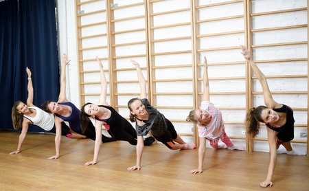 Group of young sports woman does an extension exercise at the Swedish wallの写真素材
