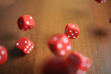 Several rolling red dice fall on a tableの写真素材