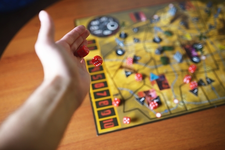 Several rolling red dice fall on a table with boardgame. Gameplay moments