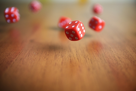 Several rolling red dice fall on a tableの写真素材