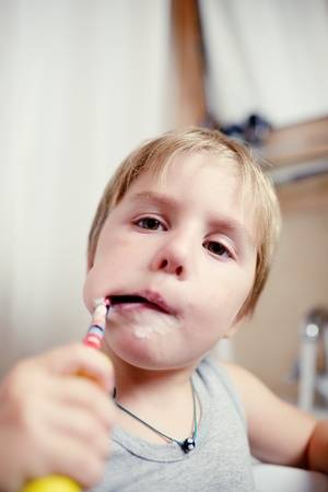 Little boy brushing teeth in bath with electric brushの写真素材