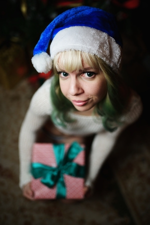 Sexy young girl gives gift under Christmas treeの写真素材