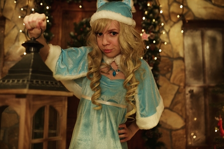 Snow Maiden holds lantern on doorstep of house decorated in Christmas styleの写真素材