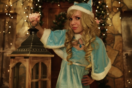 Snow Maiden holds lantern on doorstep of house decorated in Christmas styleの写真素材