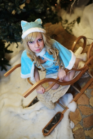 Beautiful Snow Maiden in studio Christmas interior sits on sledgeの写真素材