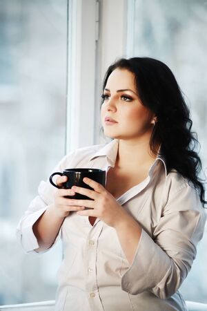 Portrait of young woman holding a cup of coffee.の写真素材