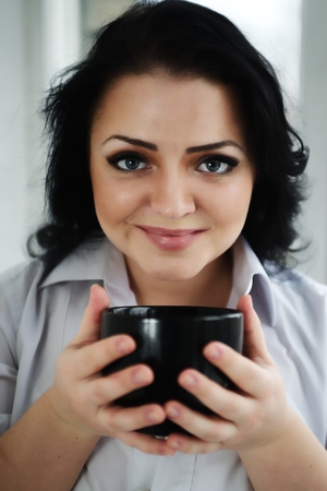 Portrait of young woman holding a cup of coffee.の写真素材